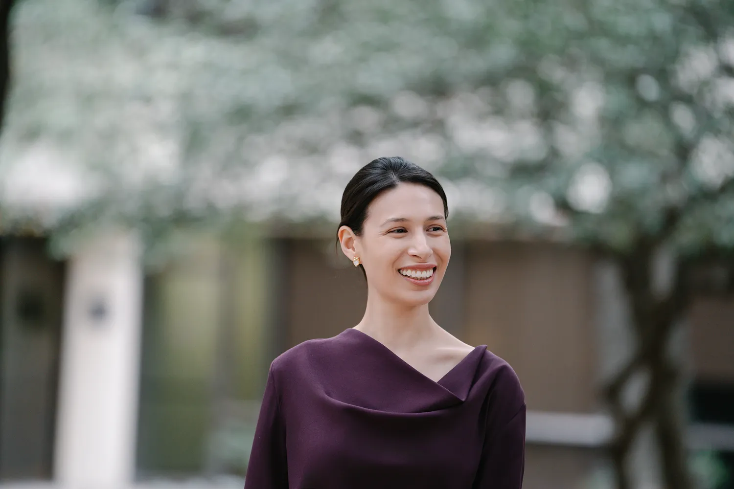 Candid, lifestyle-style headshot of a woman in a maroon dress, smiling and looking off to the side—often captured during branding photography sessions for use on websites, social media, and advertising to showcase personality and approachability.